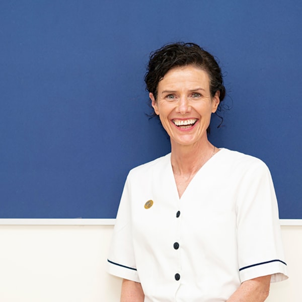 Female nurse standing in front of a noticeboard and smiling